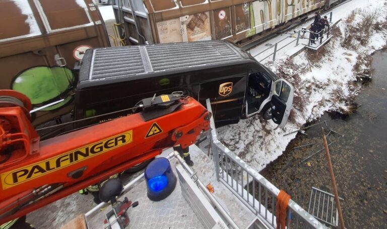 Zug erfasst Lieferwagen – Paketzusteller droht nach Crash in Fluss zu stürzen (FOTOS)